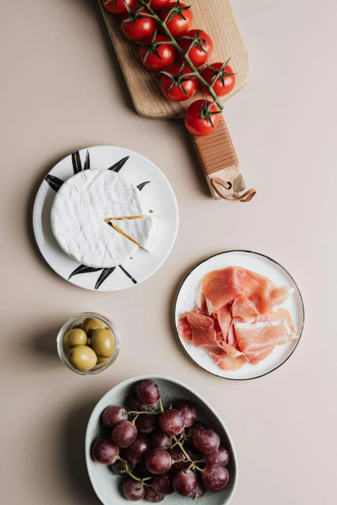 Charcuterie-style plate with cured ham, cheese, grapes, olives, and tomatoes – foods often discussed in NAFLD diets