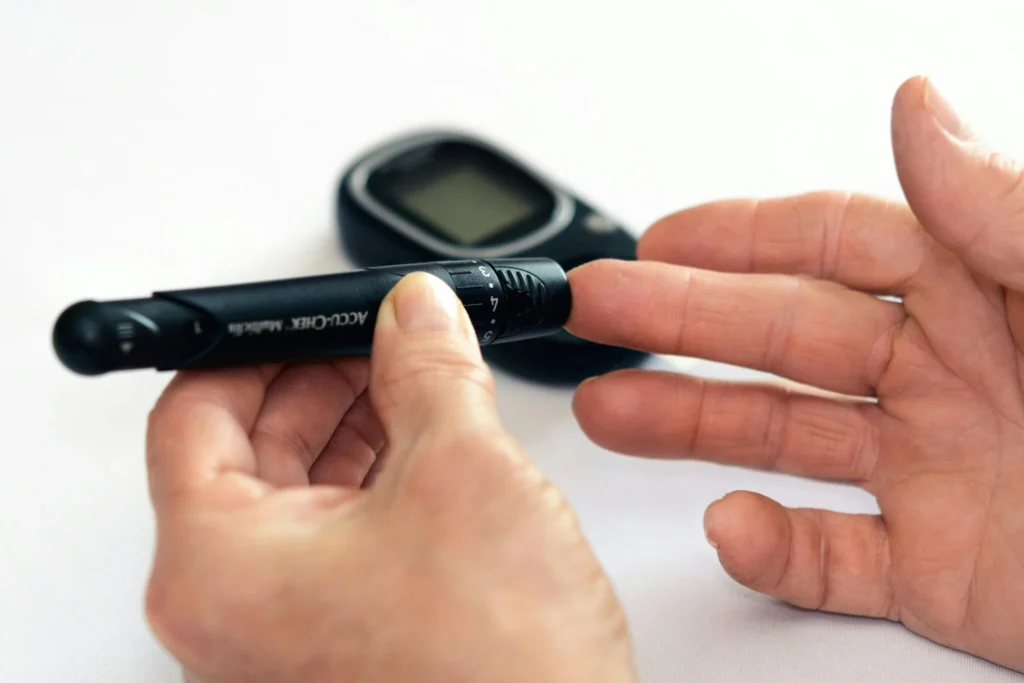 A realistic close-up of a hand using a blood glucose meter, representing type 2 diabetes as a metabolic risk factor for elevated liver enzymes (ALT, AST).