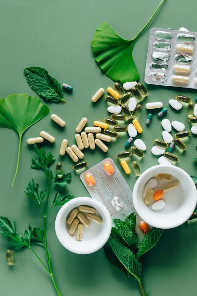 Various natural dietary supplements and herbal capsules on green background